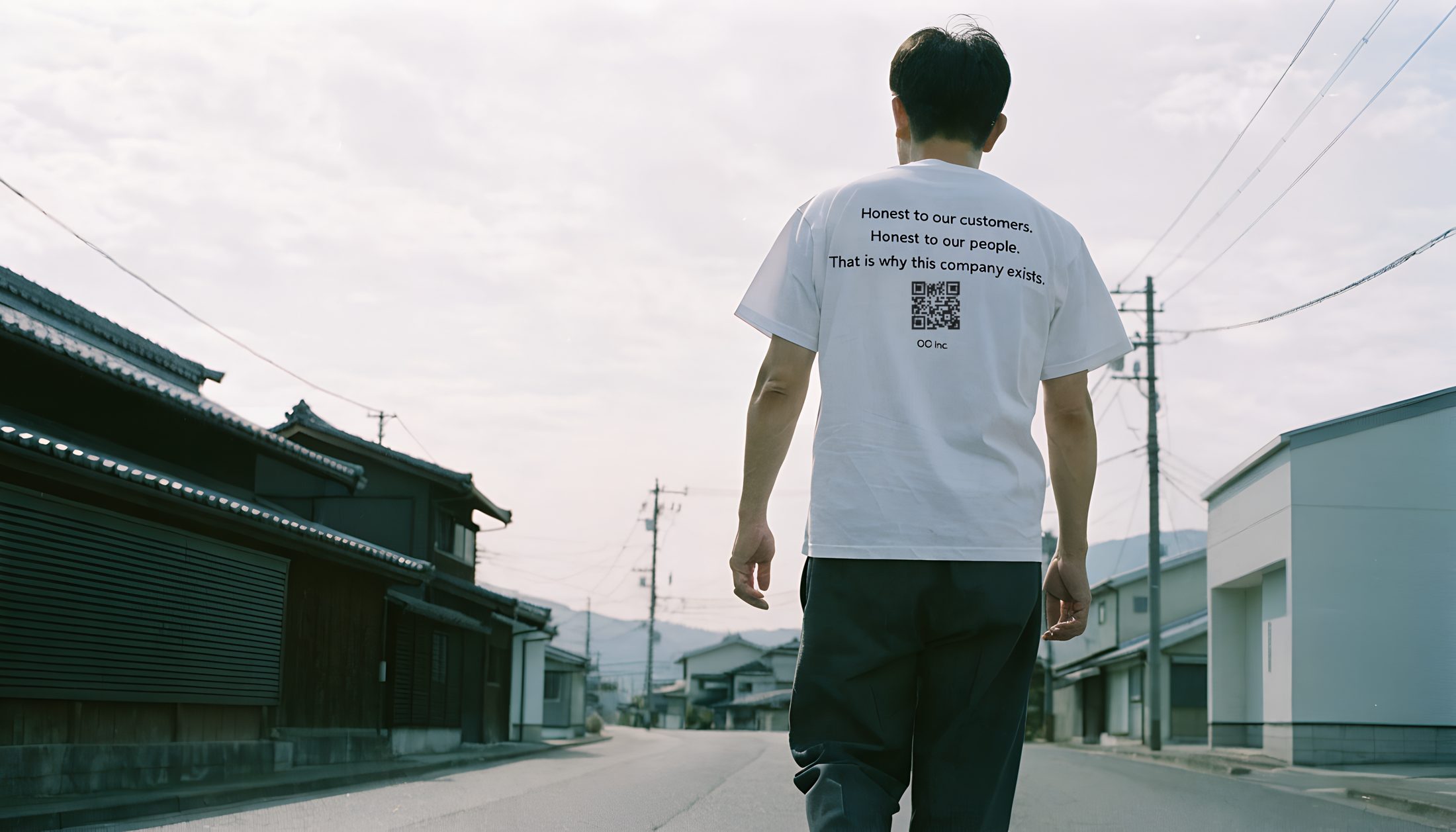 朝の町を歩く後ろ姿。背中に理念とQR（イメージ）